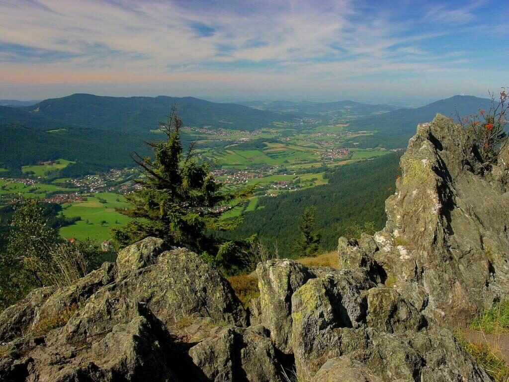 Blick von einem Felsgrat über den Lamer Winkel: Dörfer und Wiesen im Tal, dahinter die bewaldeten Bergketten des Bayerischen Waldes